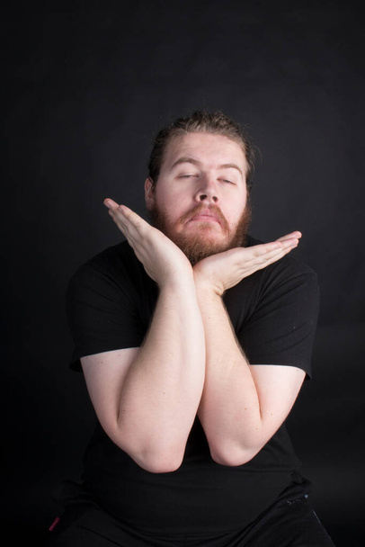Plus size male with long hair and a beard pulling a funny pose in a studio with a black background - Foto, Bild