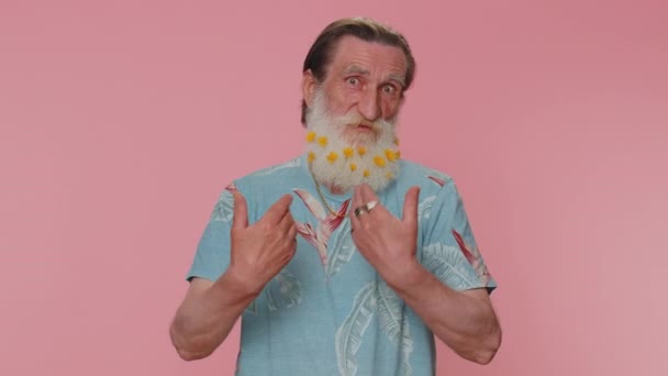 I am the best, choose me. Senior man with flowers in gray-haired beard feeling very proud pointing himself, looking self-confident, overjoyed by success. Elderly grandfather on pink studio background - Záběry, video