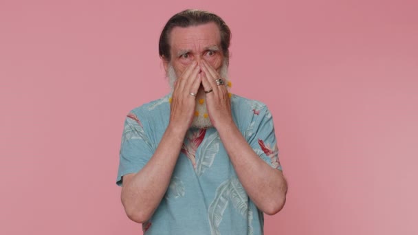 Stressed depressed mature flowered beard mature man expresses his fear and waves his hands away from danger, waving no. Scared fearful senior grandfather isolated alone on pink studio wall background - Metraje, vídeo