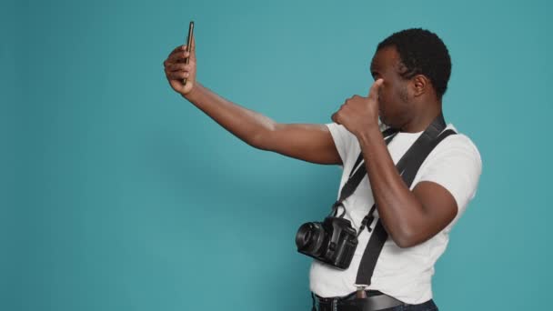 Photographer taking pictures using smartphone in studio, holding professional camera to pose. Capturing images with dslr lens and photography equipment, leisure fun activity. Focused view. - Felvétel, videó