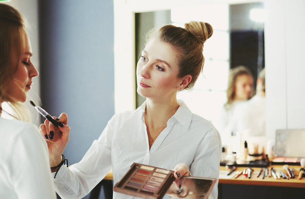 make up artist doing professional make up of young woman. - 写真・画像