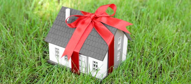 House model with red ribbon on green lawn - 写真・画像