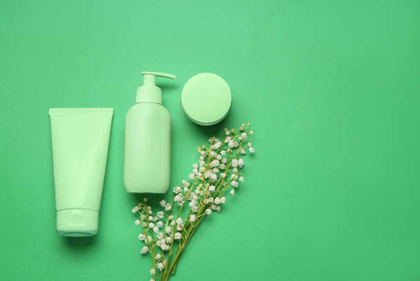 Cosmetic products and lily-of-the-valley flowers on green background - Photo, Image