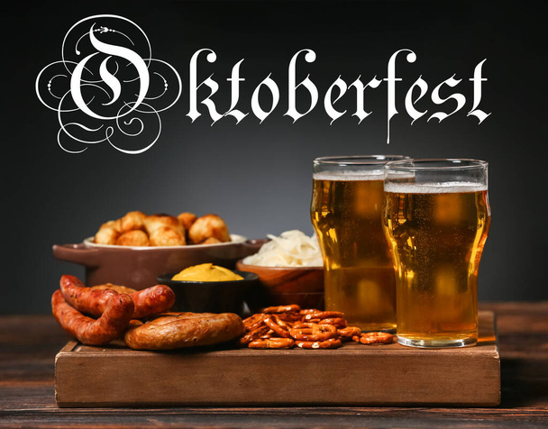 Glasses of fresh beer and snacks on table against dark background. Oktoberfest celebration - Fotó, kép