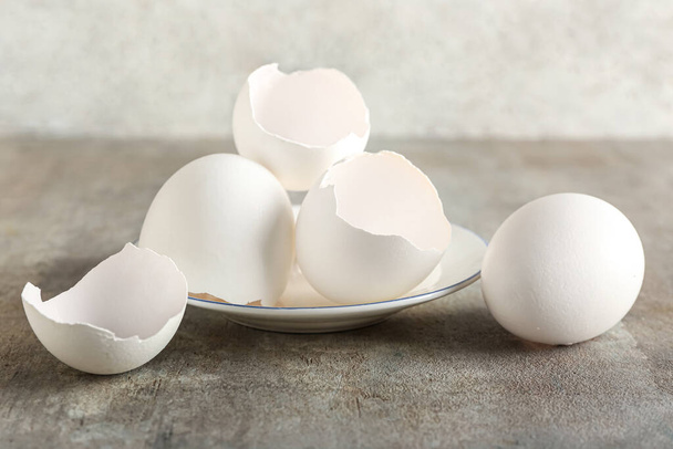 Plate with broken egg shells on grunge background - Foto, Imagem