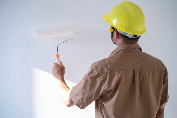 Painter man painting on white wall interior working new house with copyspace - Photo, image