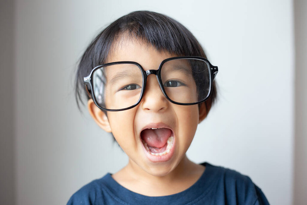 Happy facial face of little boy with big glasses on white background funny emotion - Zdjęcie, obraz