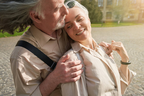 Aged man putting hands on shoulders of his partner and looking forward at the building - Foto, imagen