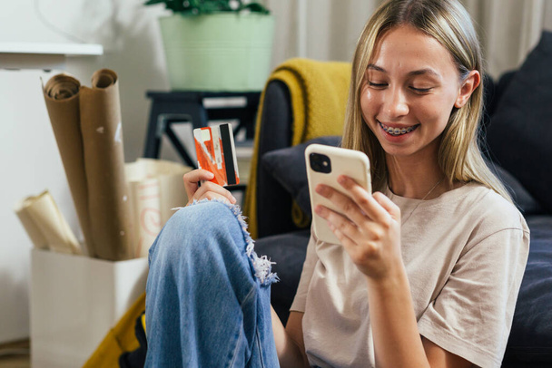 smiling teenager using smartphone for online shopping from her home - Valokuva, kuva