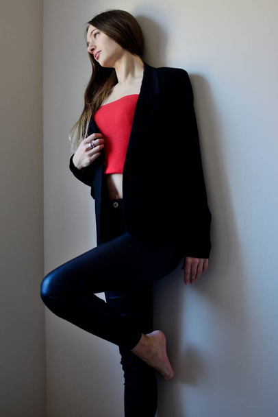 Портрет молодой женщины внутри квартиры, стоящей у стены. Фотосессия Interrior.  - Фото, изображение
