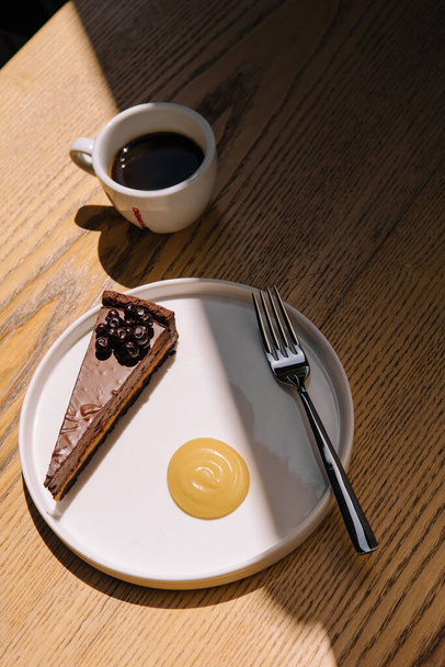 Chocolate cake with a coffee cup on wooden table - Foto, afbeelding
