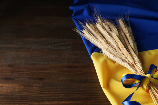 Ukrainian flag with spikelets with ribbons on wooden background - Foto, Imagen