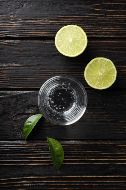 Glass of water, lime and leaves on wooden background - Foto, Bild