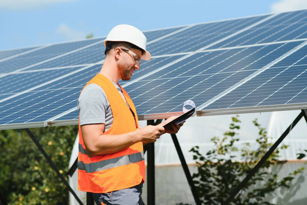 Male engineer in protective helmet installing solar photovoltaic panel system. Alternative energy ecological concept - Foto, afbeelding