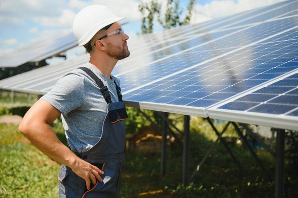 Male engineer in protective helmet installing solar photovoltaic panel system. Alternative energy ecological concept - Foto, Imagen