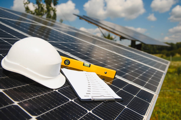 Solar cell contractor document with orange engineering team helmet on solar cells panels. Renewable energy and ecology concept - Fotó, kép