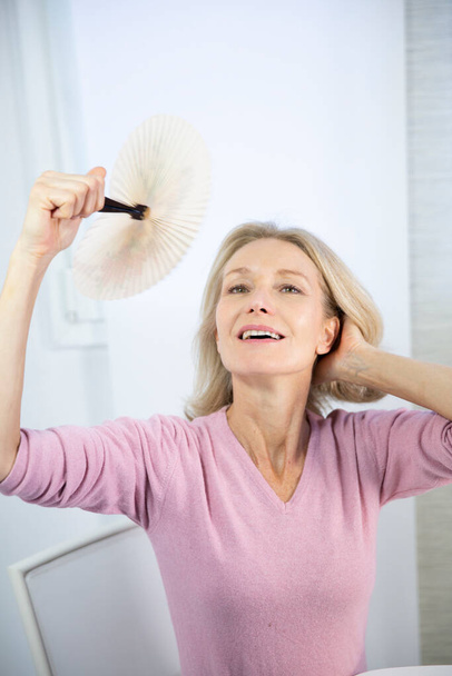 A menopausal woman having a hot flush. - Foto, imagen