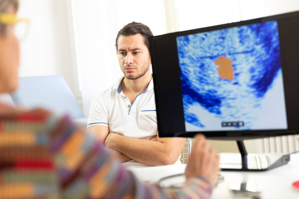 Man consulting a female doctor for prostate ultrasound examination. - 写真・画像