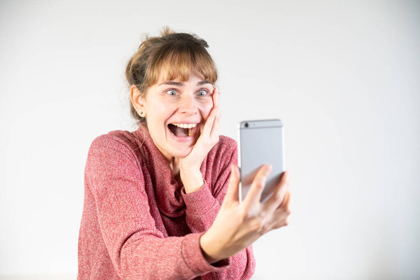 Extremely joyful woman at the sight of her new smartphone. - Photo, Image
