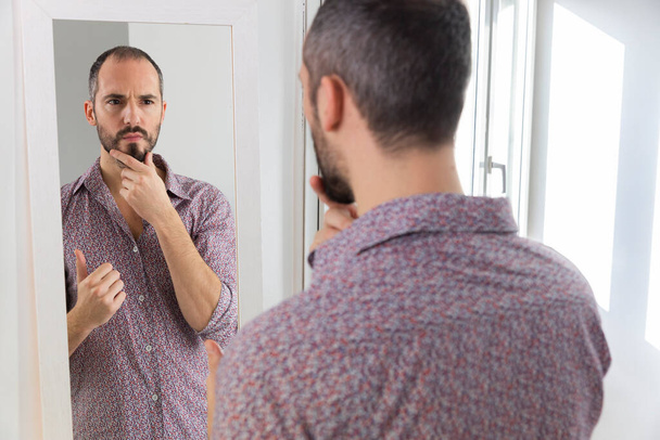 Человек, смотрящий в зеркало, чтобы придать ему уверенности в себе. - Фото, изображение
