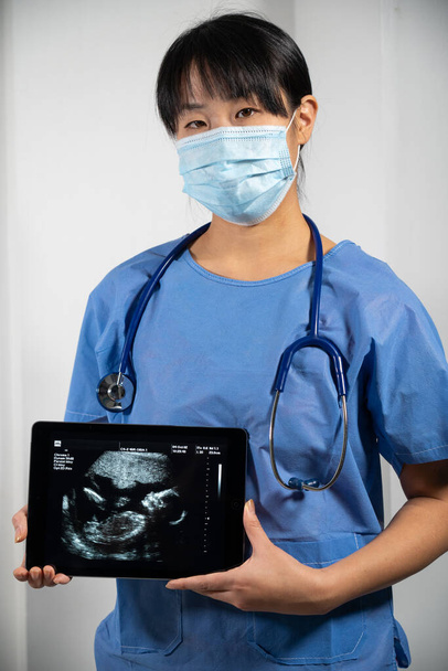 Female doctor holding a screen with fetal ultrasound - Photo, image