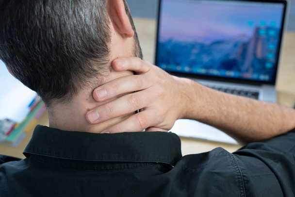 A man at his desk with neck pain. - Photo, image