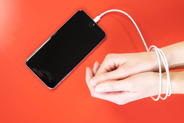 Woman's hands tied by the cord for charging a smartphone. - 写真・画像