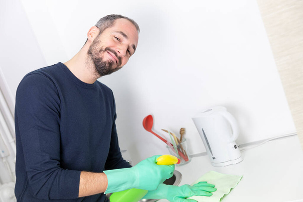 Ένας άνθρωπος που χρησιμοποιεί προϊόντα καθαρισμού για να καθαρίσει. - Φωτογραφία, εικόνα