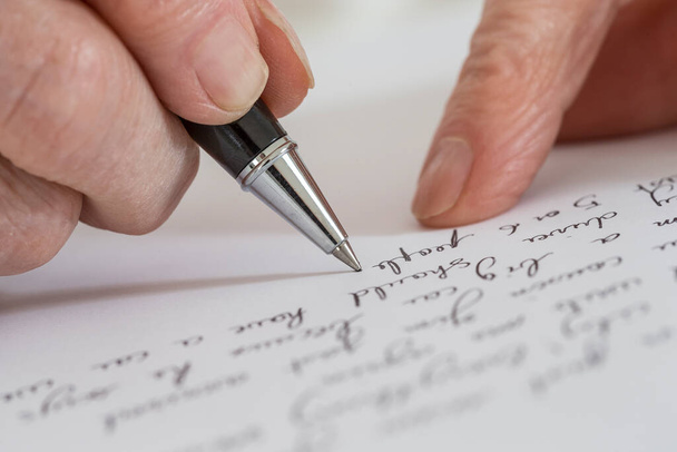 Senior woman writing on a white sheet. - Фото, зображення