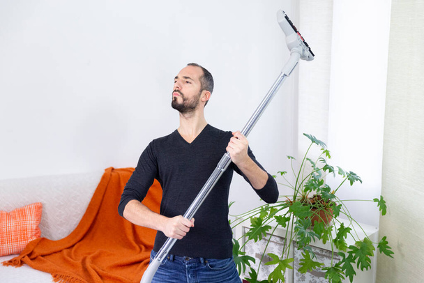 A man pretending to be a soldier with a vacuum cleaner. - Foto, Imagen