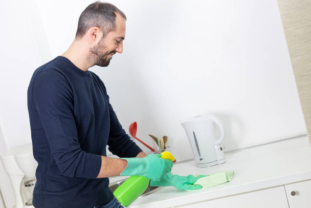 Ένας άνθρωπος που χρησιμοποιεί προϊόντα καθαρισμού για να καθαρίσει. - Φωτογραφία, εικόνα