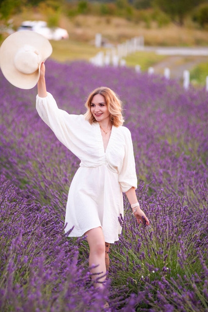 beautiful girl in a white dress and hat in a lavender field at sunset - Фото, зображення
