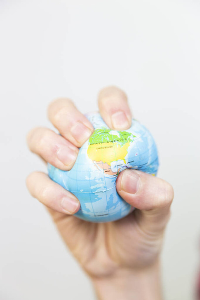 A man gripping a stress ball in the shape of the earth. - Foto, afbeelding