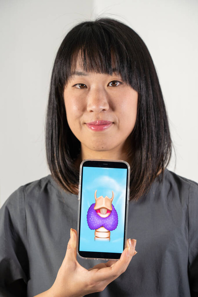 Женщина держит экран с рисунком щитовидной железы и гортани - Фото, изображение