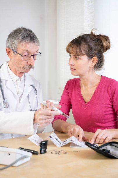 Diabetologist teaching a diabetic woman to use the tools to treat her diabetes. - 写真・画像