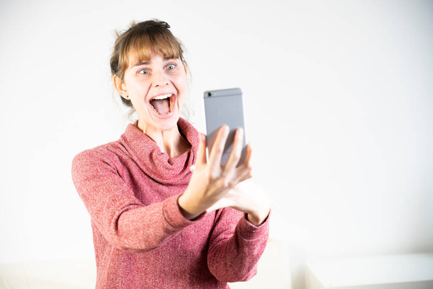 Extremely joyful woman at the sight of her new smartphone. - Foto, Bild