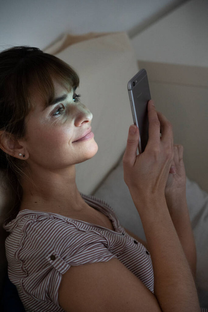 Woman at night admiring her lit smartphone. Addictive behavior. - Foto, Bild