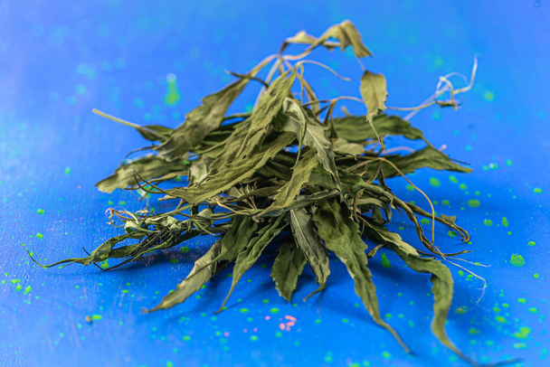 Cannabis, close up of a pile of dried cannabis leaves on a blue background. - Foto, Bild