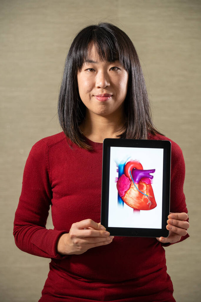 Woman holding a screen with a heart - 写真・画像