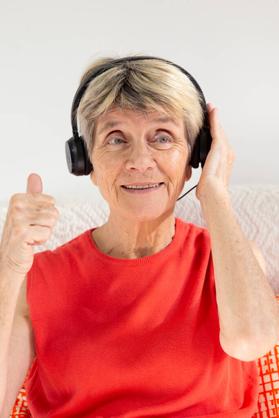 A woman expressing joy while listening to music in headphones. - Foto, afbeelding