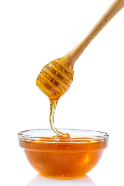 Close-up of honey and wooden honey stick. - Foto, afbeelding