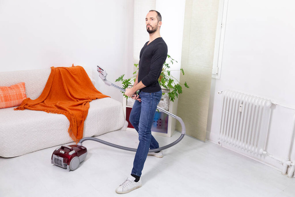 A man pretending to be a soldier with a vacuum cleaner. - Foto, afbeelding