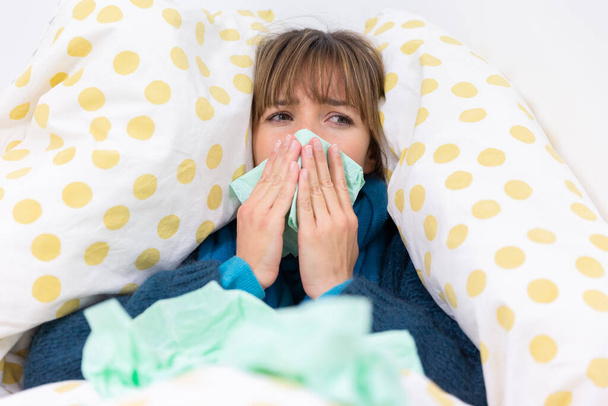 Молода жінка в ліжку страждає від застуди з хустками
. - Фото, зображення