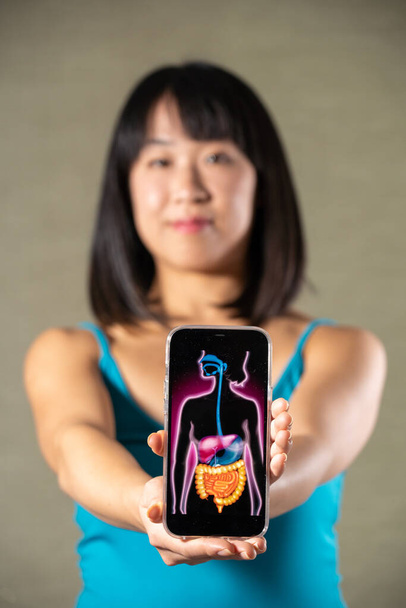 Woman holding screen with drawing of digestive system - Photo, image
