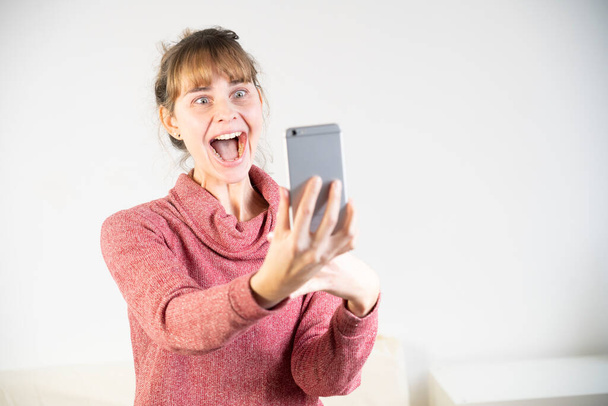 Extremely joyful woman at the sight of her new smartphone. - Foto, Bild