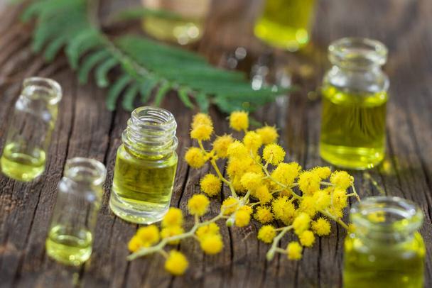 Mimosa essential aroma oil on wooden background - Foto, Bild