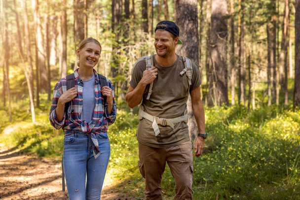 young couple with backpacks on a hike in forest. backpacking trip. summer adventure vacation - Foto, Imagem