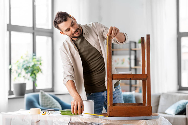 repair, diy and home improvement concept - man with ruler measuring old round wooden table for renovation - Fotoğraf, Görsel