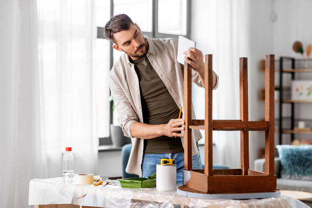 rénovation de meubles, bricolage et concept d'amélioration de la maison - homme avec une vieille table en bois écrit sur ordinateur portable - Photo, image