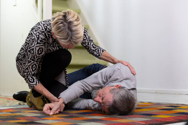 Μια ηλικιωμένη γυναίκα βοηθάει έναν ηλικιωμένο άντρα που έπεσε από τις σκάλες.. - Φωτογραφία, εικόνα